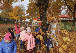 Przedszkolaki podczas zabawy kolorowymi liśćmi